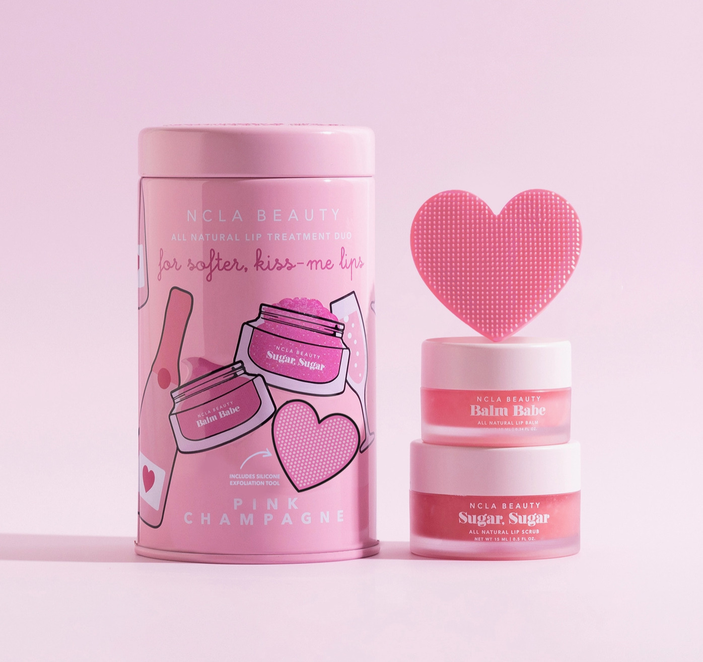 Pink cosmetic lip scrub set with 'NCLA Beauty' on a light pink background